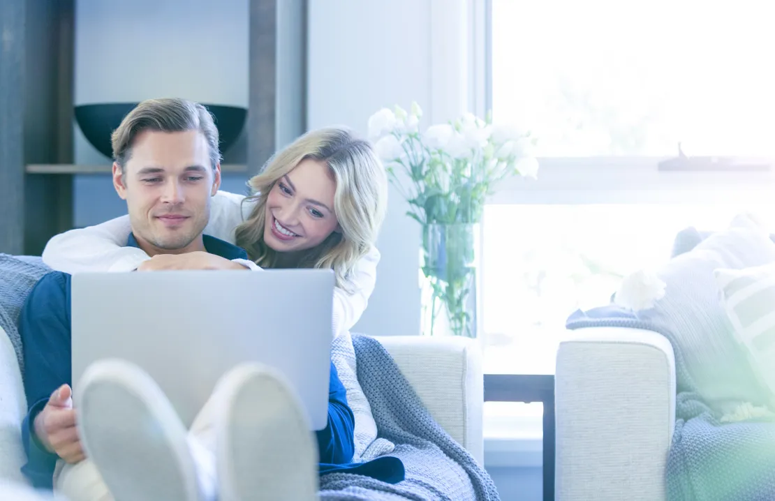 Young couple sitting on the sofa looking at a laptop