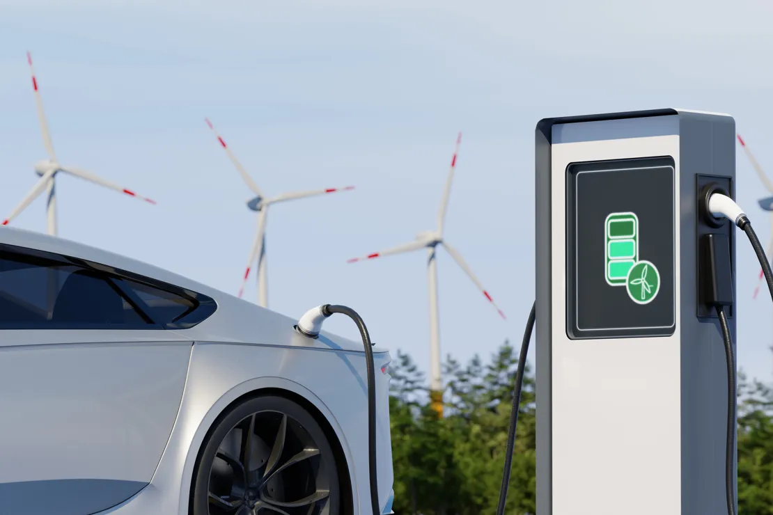 Car charging with wind turbines in the background